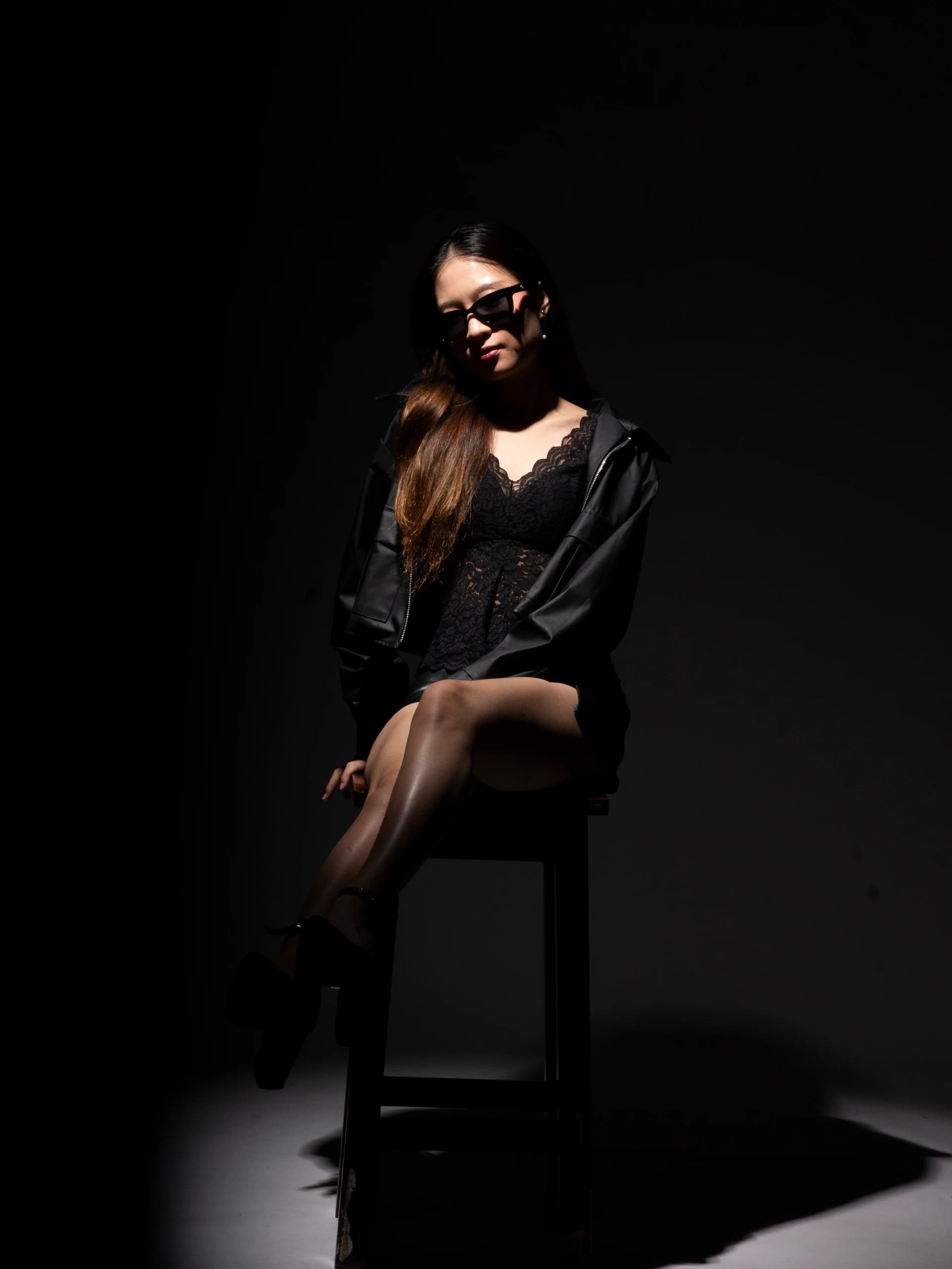 Fashion — Seated fashion portrait in black styling against a dark studio